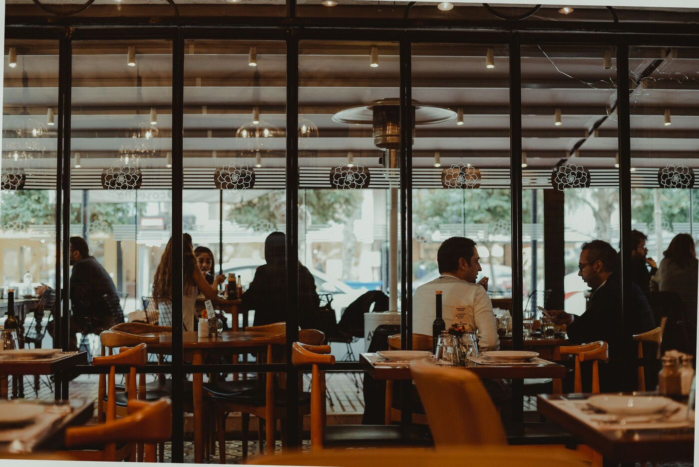 طاهٍ يُحضّر طبقًا عالميًا في مطبخ مطعم راقٍ بأبوظبي أمام زبائن من جنسيات متنوعة